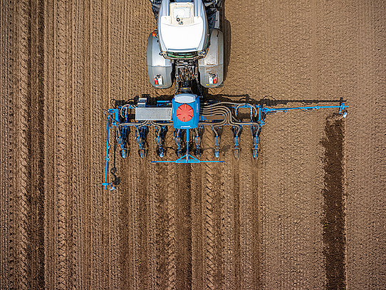 Aufnahme von oben eines Traktors beim Mais anbauen auf einem Feld.